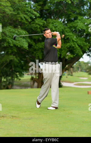 Caucasian man swinging golf club Banque D'Images