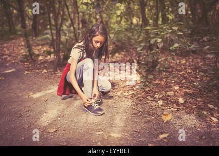 Mixed Race girl attacher ses lacets sur chemin de terre Banque D'Images