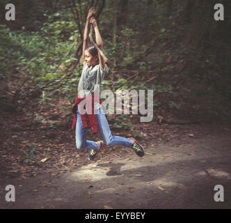 Mixed Race girl balançant d'arbre branche sur chemin de terre Banque D'Images