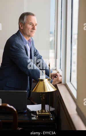 Caucasian businessman looking out office window Banque D'Images