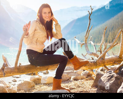 Caucasian girl smiling on log à Lake Louise, Banff, Alberta, Canada Banque D'Images