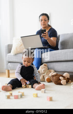 Mixed Race mother and baby son relaxing in living room Banque D'Images