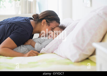 Mixed Race mother kissing baby son on bed
