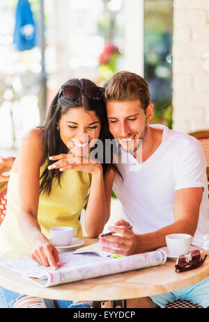 Hispanic couple reading map at cafe Banque D'Images