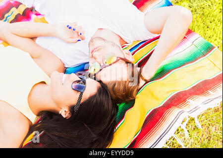 Hispanic couple laying on blanket in park Banque D'Images