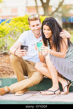 Couple l'utilisation de téléphones cellulaires sur le trottoir Banque D'Images