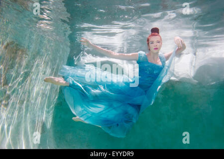 Sous-vue de Caucasian woman in dress swimming in pool Banque D'Images