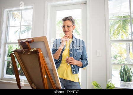 Artiste peinture sur chevalet dans chambre soleil Banque D'Images