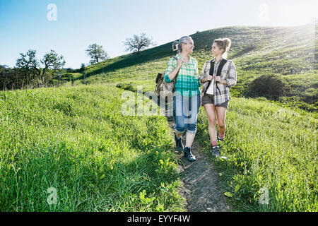 Caucasian mother and daughter walking on grassy hillside Banque D'Images