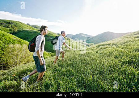 Caucasian father and son walking on grassy hillside Banque D'Images