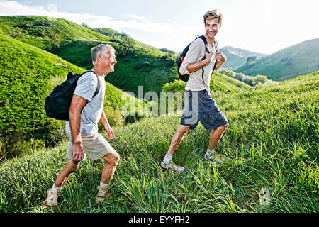 Caucasian father and son walking on grassy hillside Banque D'Images