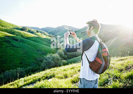 Caucasian man photographing vue panoramique à partir de la colline rural Banque D'Images