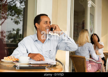 Businessman talking on cell phone in cafe Banque D'Images