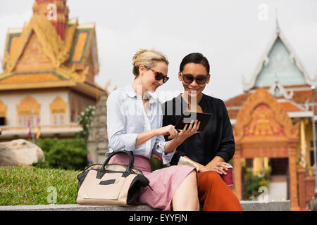 Businesswomen using digital tablet près de temple, Phnom Penh, Cambodge Banque D'Images