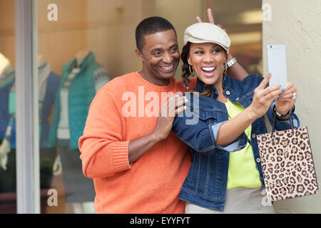 Smiling couple en tenant l'extérieur selfies store Banque D'Images