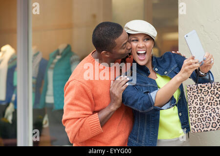 Smiling couple en tenant l'extérieur selfies store Banque D'Images