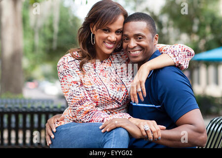 Smiling couple hugging on park bench Banque D'Images
