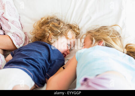 Frère et soeur de race blanche jouant sur le lit Banque D'Images