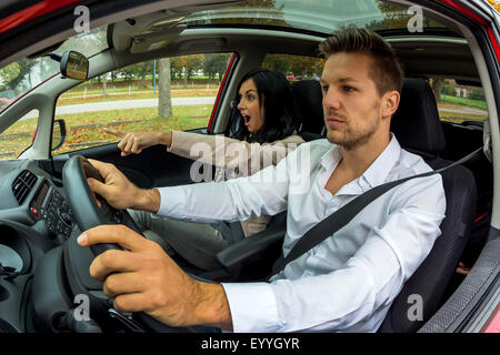 Jeune homme conduisant sa voiture avec jeune femme gesticulant comme co-pilote, Autriche Banque D'Images