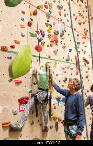Woman helping daughter escalader un mur de pierre à l'intérieur Banque D'Images