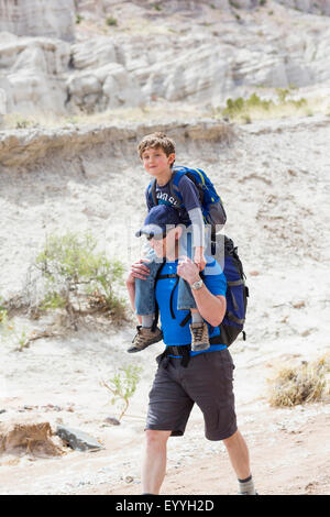 Woman carrying son on shoulders on dirt path Banque D'Images