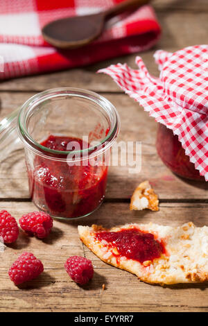 Confiture de framboises à la main dans le bocal et le biscuit aux amandes Banque D'Images