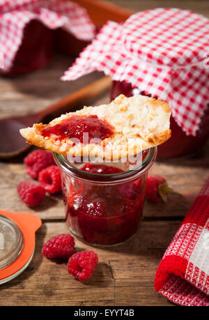 Confiture de framboises à la main dans le bocal et le biscuit aux amandes Banque D'Images