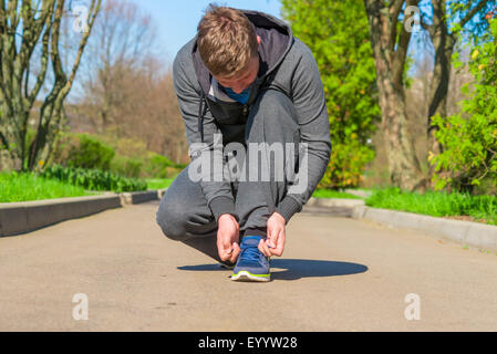 Portrait d'un athlète attachant lacets sur un tapis roulant Banque D'Images