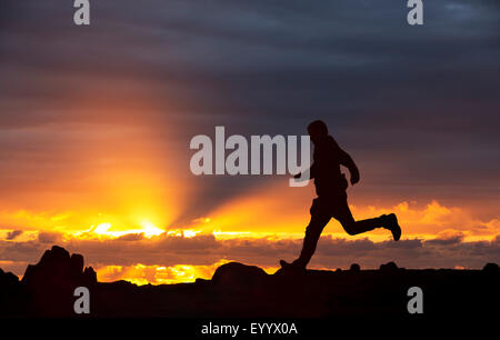 Un homme court sur éboulis rouge au coucher du soleil, Lake District, UK Banque D'Images