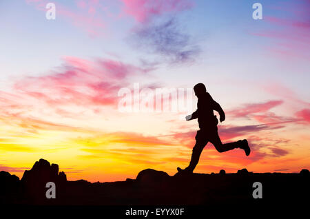 Un homme court sur éboulis rouge au coucher du soleil, Lake District, UK Banque D'Images