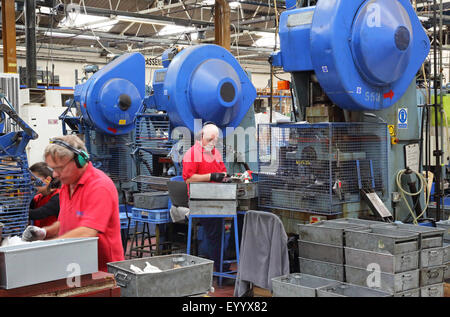 Travailleurs dans une usine de fabrication de composants métalliques pour l'industrie de la construction en acier à l'aide de grandes machines pressantes Banque D'Images