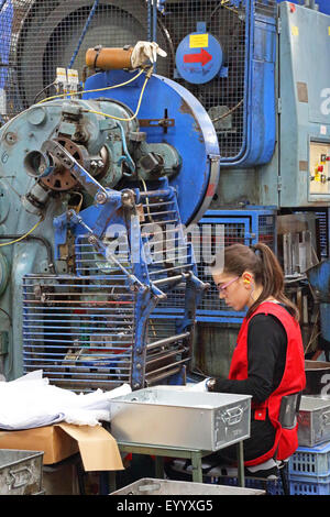 Une jeune travailleuse fait de composants métalliques pour l'industrie de la construction à l'aide d'une grosse machine en appuyant sur l'acier Banque D'Images