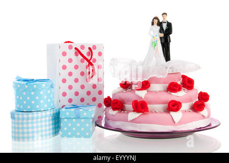 Couple sur le dessus de gâteau de mariage rose avec des cadeaux plus isolé sur fond blanc Banque D'Images