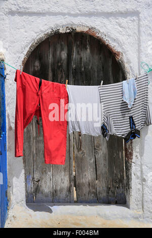 Lavage de couleur accroché sur une corde à linge devant une vieille porte en bois, la Grèce, les Cyclades, Santorin Banque D'Images