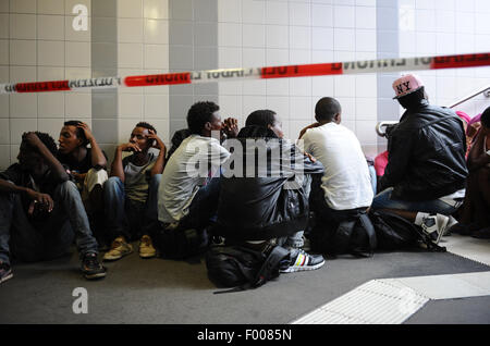 Rosenheim, Allemagne. Le 04 août, 2015. Un groupe de réfugiés de différents pays en attente d'être enregistré est assis sur un escalier de la gare de Rosenheim, Allemagne, 04 août 2015. La police allemande a ramassé autour de 150 réfugiés de différents pays dans un train entrant de Vérone. Après avoir été fouillé et enregistrés, ils ont reçu un document d'identification à un bureau de la Police Fédérale Allemande et a été envoyé à l'établissement d'accueil des réfugiés à Munich, où ils peuvent faire une demande d'asile. Photo : Andreas GEBERT/dpa/Alamy Live News Banque D'Images