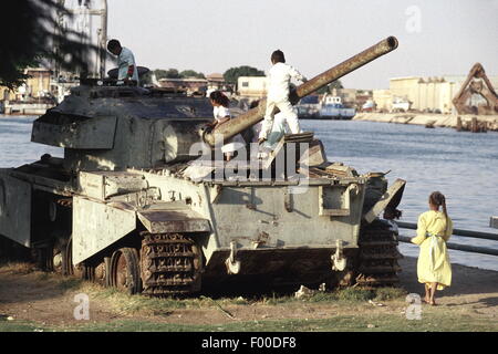 Canal de Suez, Egypte - les enfants égyptiens jouer sur les ruines d'un réservoir à l'extrémité sud du Canal de Suez, témoins de guerres passées entre l'Égypte et Israël. Le canal de Suez a été fermé à la navigation à partir de 1967 jusqu'à la fin des années 1970, en raison de débris de navires coulés dans le canal. Une des merveilles du génie construit en 1869 par le français Ferdinand de Lesseps, elle est aujourd'hui l'objet d'une mise à niveau importante par l'ajout d'un canal parallèle pour augmenter le trafic et de réduire les temps d'attente. Banque D'Images