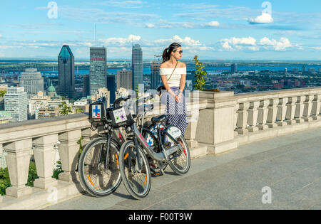 Une jeune femme asiatique sur la terrasse du belvédère Kondiaronk, sur Mont-Royal, à Montréal, à côté des vélos Bixi. Banque D'Images