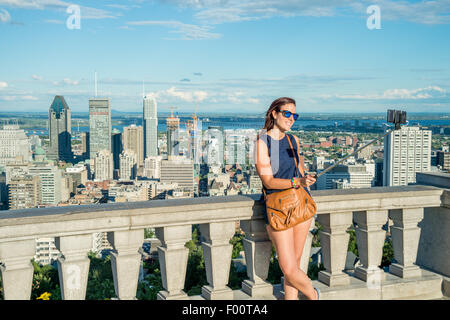 Jeune femme à l'aide d'un bâton selfies devant Montréal Skyline, Kondiaronk Belvedere. Banque D'Images