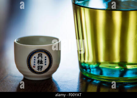 Une bouteille de saké japonais, d'alcool brassée par la brasserie de saké Gekkeikan Kyoto, avec un souci de tasse en céramique portant le logo de l'entreprise. Banque D'Images