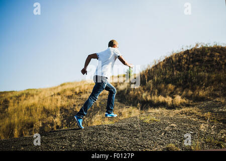 Jeune homme dans les vêtements de running uphill Banque D'Images