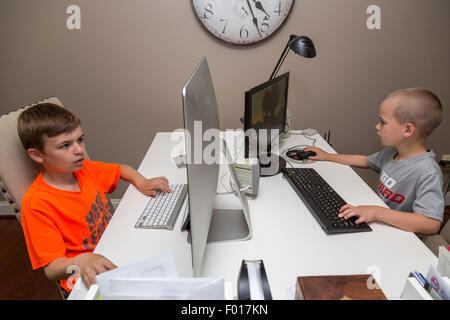 Deux frères, neuf et sept ans, jouer à des jeux vidéo à la maison après l'école. M. Banque D'Images