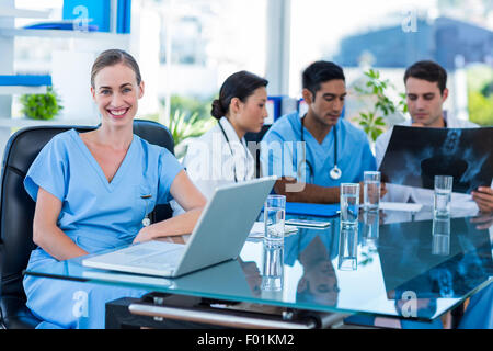 Happy doctor looking at camera tandis que ses collègues se penche sur Xray Banque D'Images