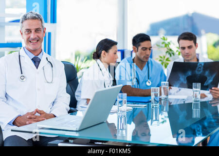 Happy doctor looking at camera tandis que ses collègues se penche sur Xray Banque D'Images