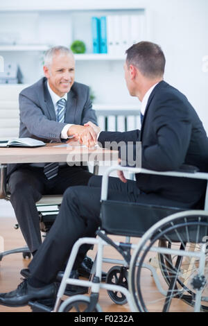 Woman in wheelchair shaking hands with collègue Banque D'Images