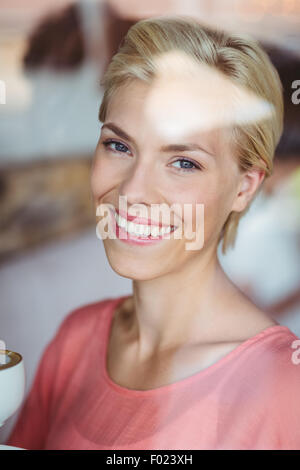 Happy blonde woman smiling at camera et tenant une tasse de café Banque D'Images