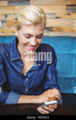 Smiling jolie blonde envoyer un message texte Banque D'Images