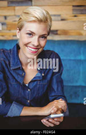 Smiling jolie blonde envoyer un message texte Banque D'Images