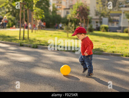 Garçon jouant au football dans la rue Banque D'Images