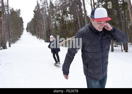 Jeune homme tirant sur l'homme des neiges avec corde Banque D'Images