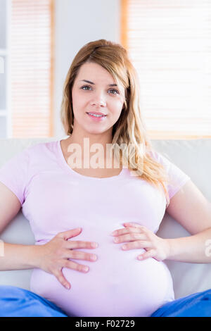 Pregnant woman looking at camera with hands on belly Banque D'Images